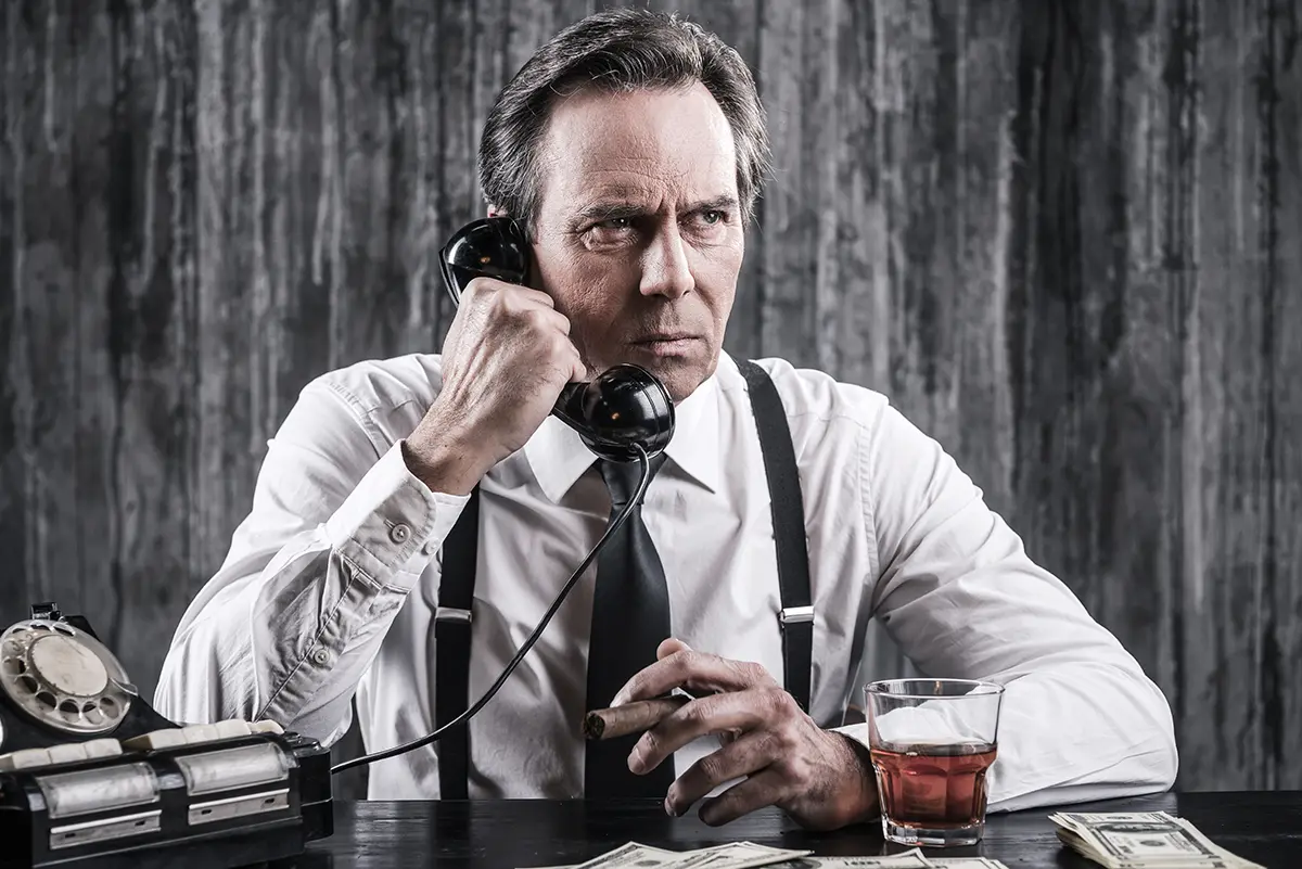 A man sitting at the desk, talking on the corded phone