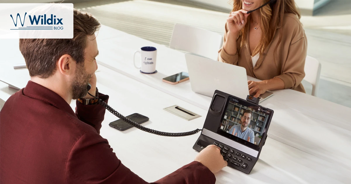 Two colleagues working together on office phone and headphones