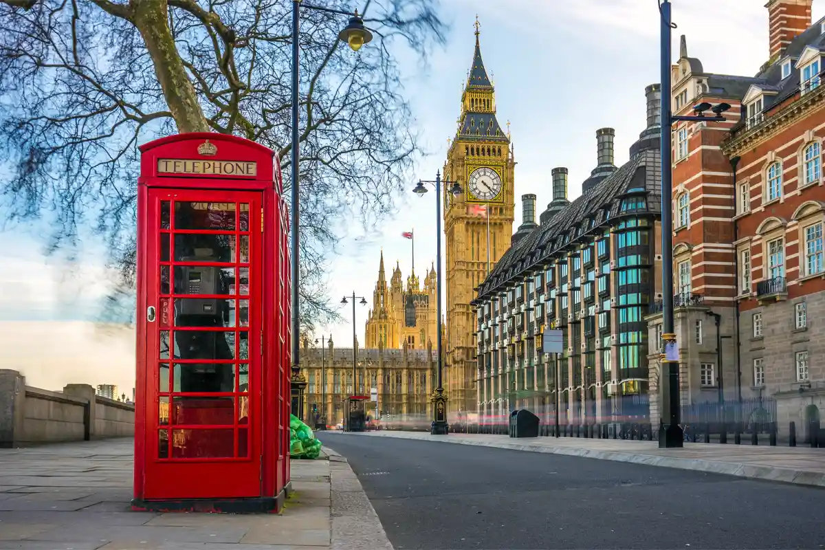 The British old red telephone box with the Elizabeth Tower at background in the center of London